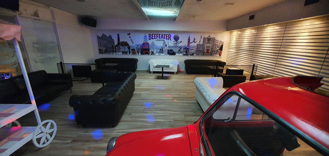 El salón del pub, con sofás capitoné y un SEAT 600 rojo